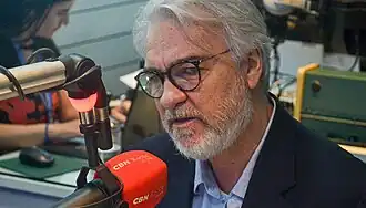 Foto de Jamildo Melo, de terno, falando em microfone vermelho com o símbolo da CBN Recife