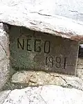 Assinatura em obra de escultura em barro coberto de musgo no Jardim do Nêgo.