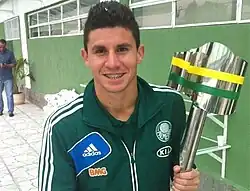 Um homem segurando uma taça de futebol e sorrindo