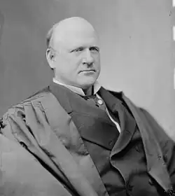 A balding man in his fifties wearing black judicial robes