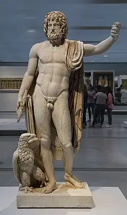 Marble statue of a bearded man, standing, with his right arm raised above his head.