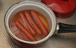 Salsicha tipo vienense sendo preparada em uma panela.