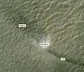 Redemoinho, visto pela HiRISE. O redemoinho se move para o canto superior à esquerda, deixando um rastro escuro na parte infrior à direita. A sombra do redemoinho is se encontra acima à sua esquerda.