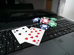 Foto de um computador portátil com cartas de baralho e fichas de poker sobre o teclado