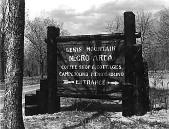 Placa de parque na qual se lê: "Montanha Lewis - Área para Negros - Cafeteria e Chalés - Locais para acampamento e piqueniques – Entrada"