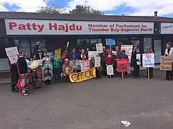 pessoas com cartazes e faixas diante de um escritório térreo