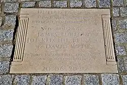 Uma placa memorial com a inscrição "Unidos para Sempre / Nunca passaremos sem lembrar de vocês / Em memória de James Furlong / Joe Ritchie-Bennett / & David Wails / Para James, Joe e David, suas famílias e todos os afetados / 20.06.2020"