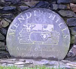 Placa circular azul desgastada com o logotipo da Área de Outstanding Natural Beauty Mendip Hills