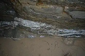 Formação rochosa formada a partir do processo de metamorfismo com veios de cristais de quartzo entre as camadas da rocha.