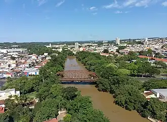 Ponte Metálica vermelha sobre Rio Mojiguaçu, ao fundo; vista do centro da cidade International Paper