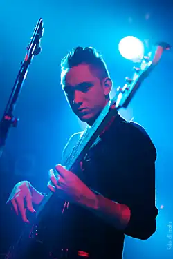 Oliver Sim (centro) em 2022 segurando o vinil de seu disco solo.