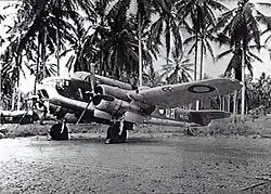 Three-quarter view of twin-engined military aircraft on jungle landing