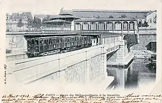 Estação da linha 1, em 1903, na extremidade do canal Saint-Martin. Ao fundo: telhado da antiga Gare de la Bastille.
