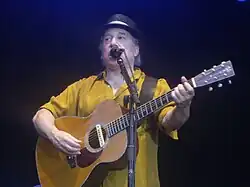 Paul Simon canta ao vivo com violão.