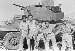 Soldados do Palmach (Brigada Yiftach) com um carro blindado do exército jordaniano, recém destruído por um PIAT, na Operação Dani, em al-Burj, 15 de julho de 1948
