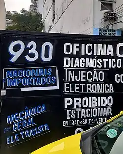 Muro de oficina mecânica com tipografia vernacular urbana.
