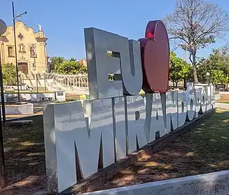Letreiro "Eu amo Mirandópolis" e igreja matriz ao fundo