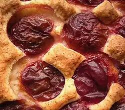 Um pedaço de bolo coberto com ameixas inteiras