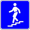 H8b — Passagem desnivelada para peões (em escada): indicação da localização da passagem desnivelada destinada ao trânsito de peões, em escada
