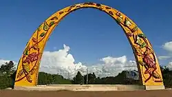 Arco na cor amarela com decoração em folhas coloridas.