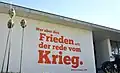 Quem busca a paz fala de guerra - citação do autor alemão Walter Benjamin na entrada.