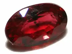 pedra brilhante de cor avermelhada e formato amendoado