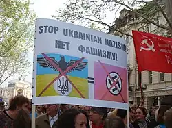 Ativistas pró-Rússia com um cartaz comparando o governo ucraniano aos nazistas e agitando uma Bandeira da Vitória