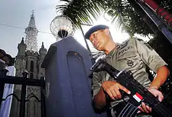 Um membro da Brimob com um fuzil Pindad SS1 guardando a Catedral de Jacarta.