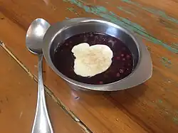 Sagu de vinho com creme e canela em um pote com uma colher