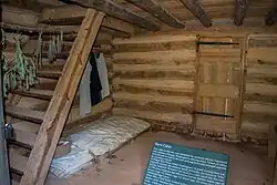 Fotografia mostrando uma cama única sobre um palete em um chão de terra