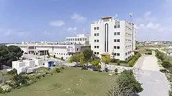 Vista da entrada sul do Hospital da Amizade Turco-Palestino e da Faculdade de Medicina da IUG. O logotipo da TİKA pode ser visto na entrada principal.