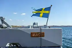 Bandeira de guerra sueca içada no pau de bandeira do navio de guerra de minas HMS Ulvön