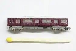 Modelo do vagão Hankyu 9000 na escala T com um palito de fósforo para comparar o tamanho.