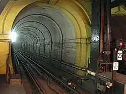 Um túnel ferroviário estreito com uma única via férrea, iluminado por uma luz branca intensa