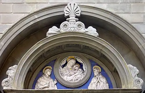 Tímpano com a imagem de uma Madona com o Menino ladeada por Santo Ivo (esq.) e São Bernardo (dir.)