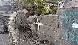 Soldado pintando a cruz em um tanque capturado.