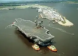USS John F. Kennedy (CV-67) na Florida sendo guiado por rebocadores em 2002.