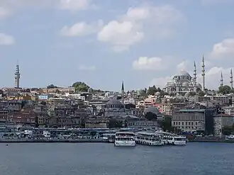 Vista do bairro de Eminönü desde o Corno de Ouro. À esquerda ergue-se a Torre de Beyazıt, ao centro encontra-se a Mesquita Yeni, com o Bazar das Especiarias (ou "Egípcio", em turco: Mısır Çarşısı). Em cima, à direita ergue-se a Mesquita Süleymaniye, a maior e mais elevada de Istambul