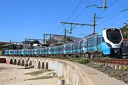 Metrorail X'Trapolis Mega passando perto da estação Kalk Bay na Cidade do Cabo