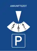 blaues Rechteck, oben die weiße Aufschrift "ANKUNFTSZEIT", darunter ein nach unten zeigendes weißes Dreieck, das auf ein weißes Kreissegment zeigt, in dem die Zahlen 5, 6 und 7 zu sehen sind, darunter schließlich ein weißes "P" in einem weißem Quadrat.