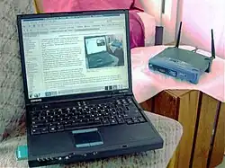 Laptop preto com o roteador ao fundo