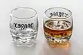 Ambigram "Cognac / Danger", simetria de espelho (eixo vertical), frente e para trás, em um conjunto de dois copos de shot. Aviso humorístico relacionado ao consumo de álcool.