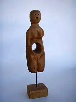 Escultura de madeira feminina com o interior do ventre oco.