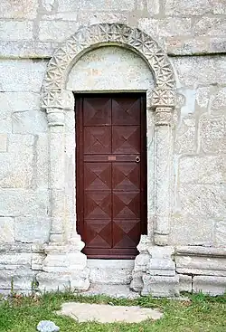 Porta enquadrada por colunas, arquivolta e impostas com motivos geométricos e tímpano liso. Igreja de Alstahaug (Nordland, Noruega)
