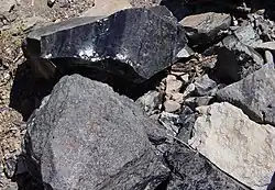 A pedra superior é obsidiana, abaixo dessa é granito e à direita mais abaixo está o riólito (cor clara).