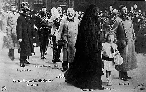 Carlos no cortejo fúnebre de Francisco José I até a Cripta dos Capuchinhos. Tradicionalmente, o novo imperador ficava sozinho atrás do caixão do falecido, seguido pelo príncipe herdeiro e pela imperatriz, mas Carlos aboliu o estilo habitual e ficou ao lado da esposa Zita e do filho Oto.[22]