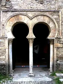Moçárabe: porta dupla com arco em ferradura com capitéis vegetalistas e alfiz a delimitar o arco. Peñalba de Santiago (el Bierzo)