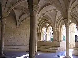 Colunas com capitéis de transição e mísulas na parede suportam as abóbadas nervuradas da sala capitular. Mosteiro de Santes Creus (Alt Camp)