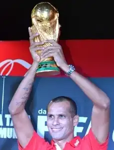 Um homem segurando uma taça dourada e sorrindo
