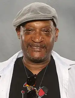 Tony Todd, um homem afro-americano, está olhando diretamente para a câmera e usando um chapéu.